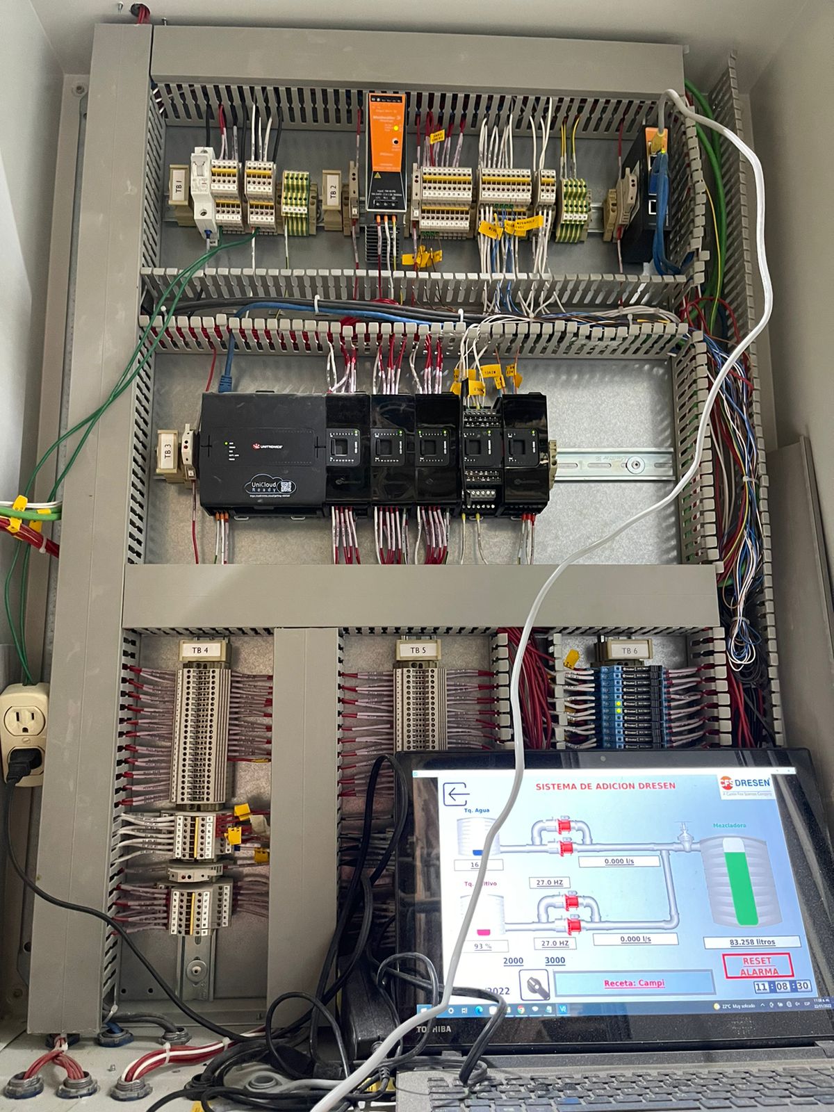Detalle de un gabinete con cableado, componentes de control y pantalla HMI